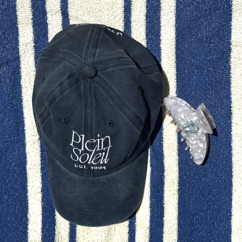 casquette bleue delavee, plein soleil broderie et pince en ecaille et acetate blanc avec strass bleu sur serviette rayee blanc et bleu