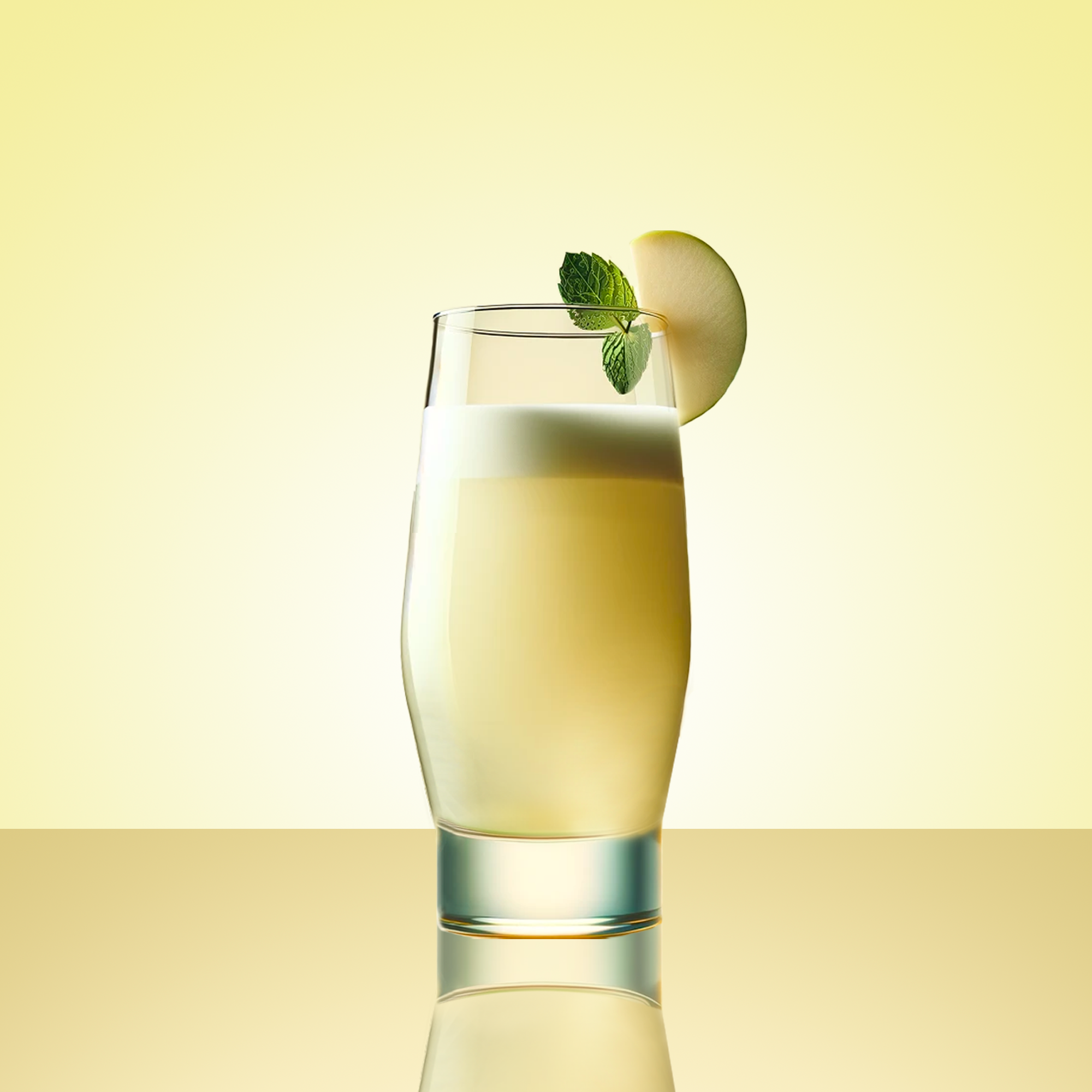 Pina Colada cocktail in a tall highball glass with green apple and fresh mint as garnish sitting against the rim of the glass. Yellow gradient background