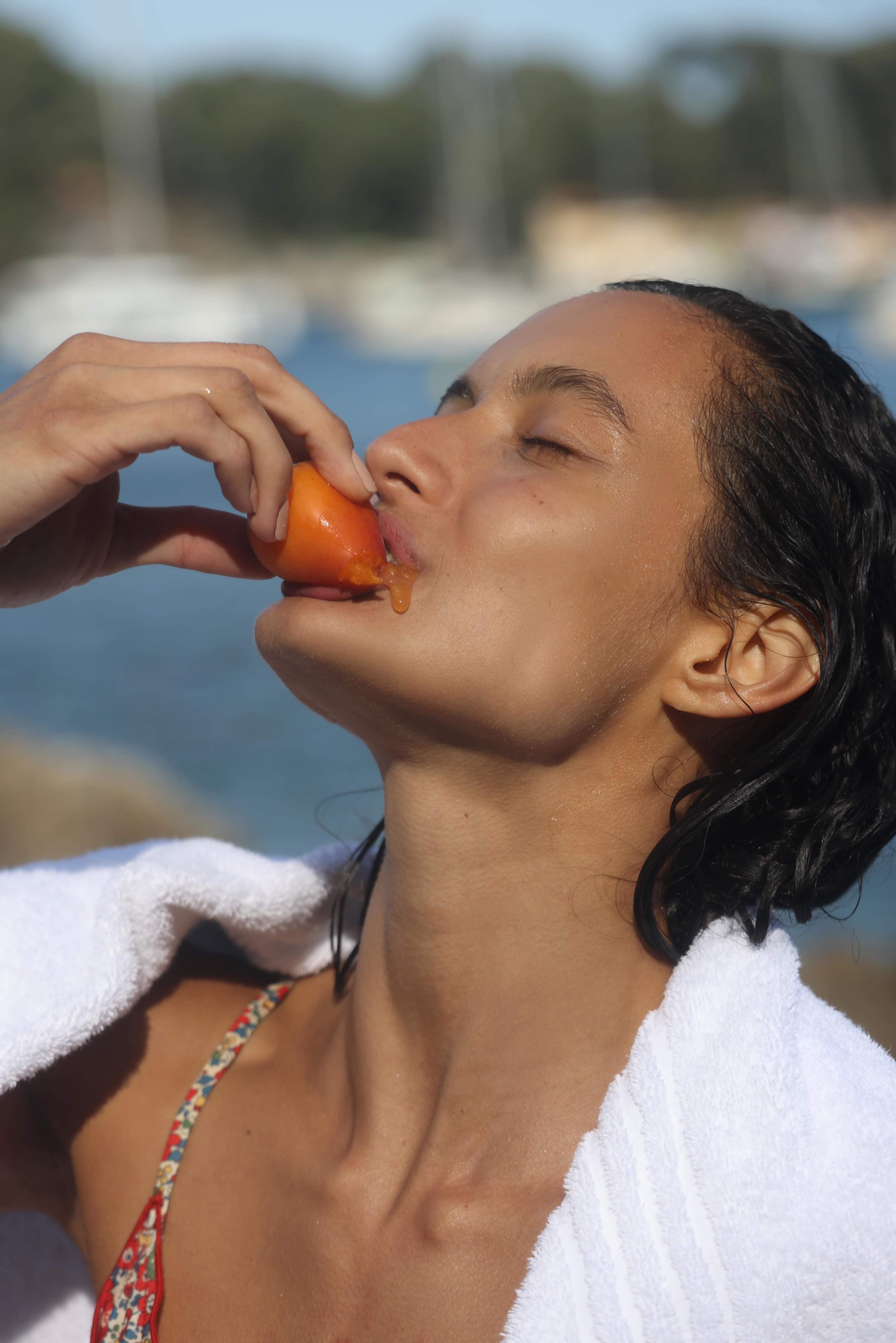 Woman eating an Apricot while by the sea